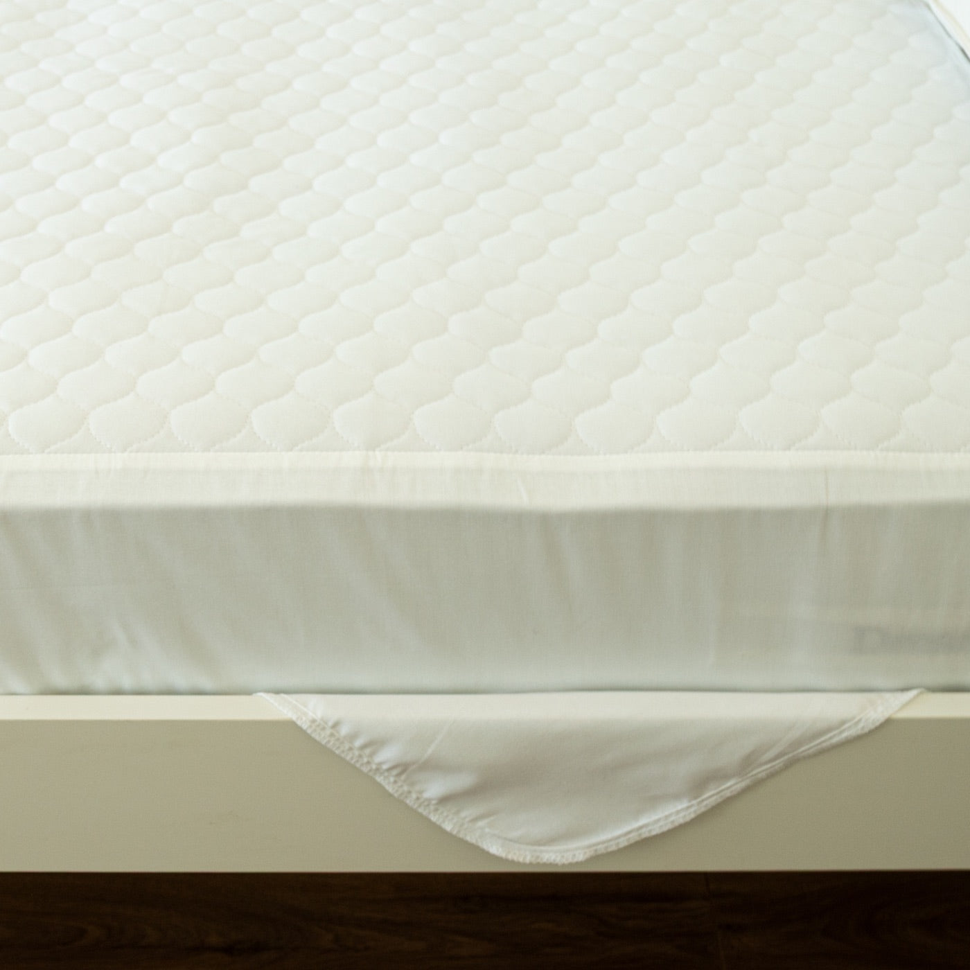 Tuck-in wing of a Bedwetz pad folded under a mattress